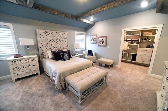 carpeted bedroom featuring a walk in closet and beam ceiling