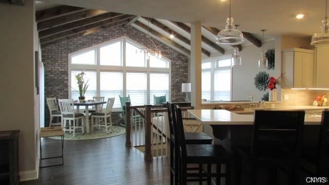 dining area with dark wood-type flooring, high vaulted ceiling, plenty of natural light, and beam ceiling