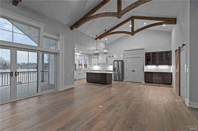 kitchen with a barn door, light hardwood / wood-style floors, dark brown cabinets, stainless steel refrigerator with ice dispenser, and a kitchen island