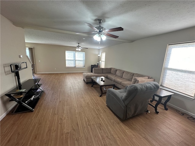 living room with a wealth of natural light, ceiling fan, hardwood / wood-style flooring, and a textured ceiling