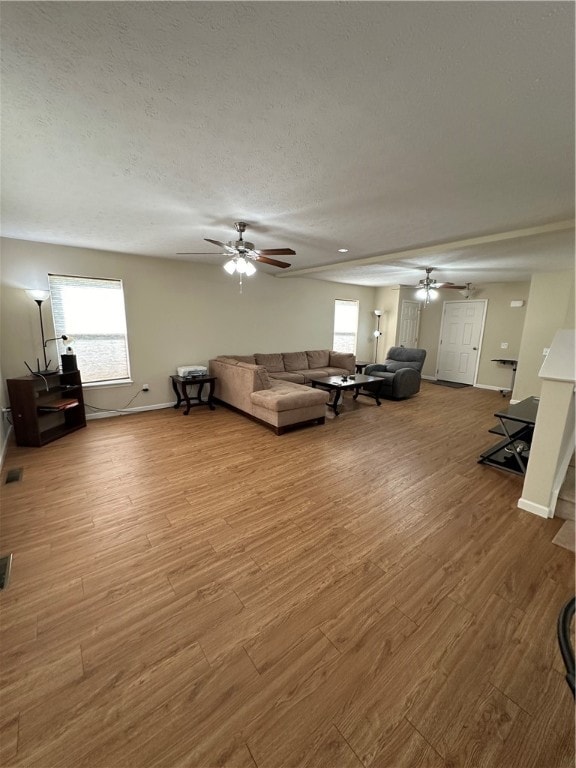 living room featuring ceiling fan, light hardwood / wood-style floors, and a textured ceiling