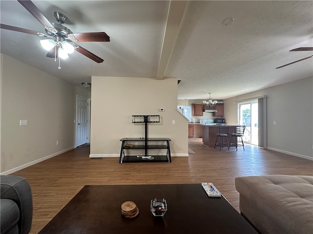 living room with a textured ceiling, ceiling fan, beamed ceiling, and hardwood / wood-style floors