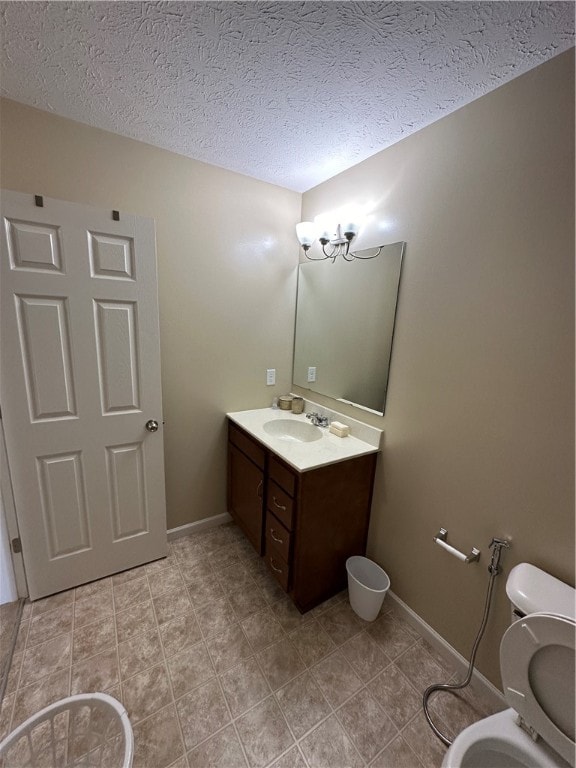 bathroom featuring toilet, a textured ceiling, and vanity