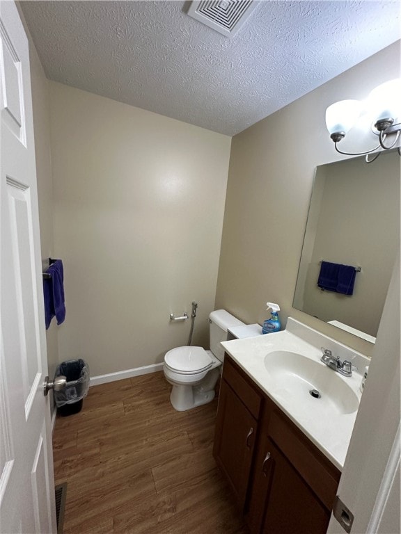 bathroom featuring wood-type flooring, toilet, a textured ceiling, and vanity