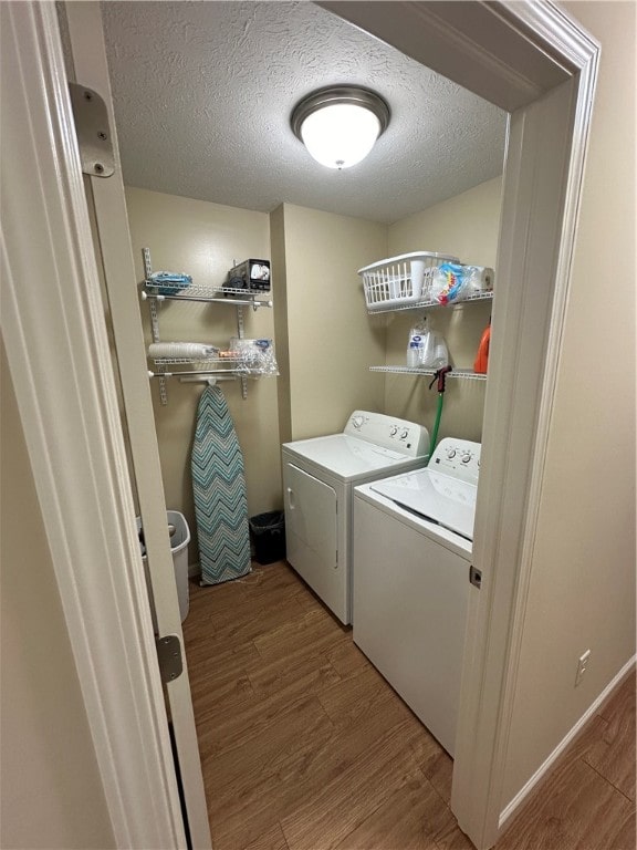 clothes washing area with hardwood / wood-style flooring, a textured ceiling, and washer and dryer