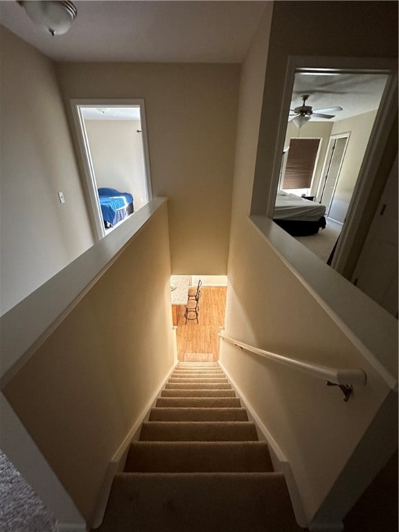 stairway with wood-type flooring and ceiling fan