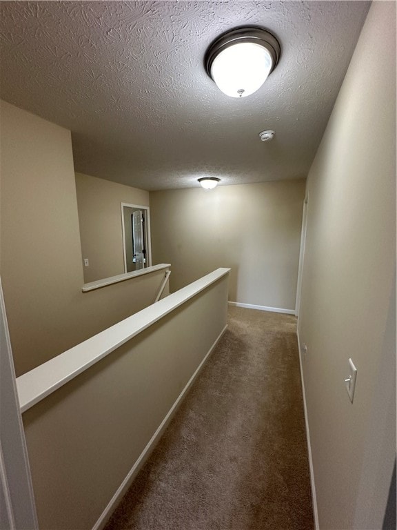 hall with a textured ceiling and carpet floors