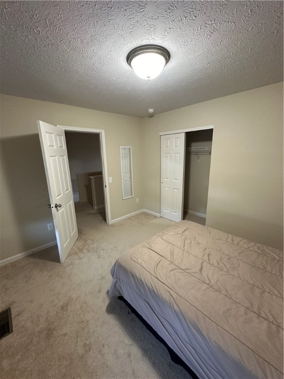 unfurnished bedroom featuring a closet, light carpet, and a textured ceiling