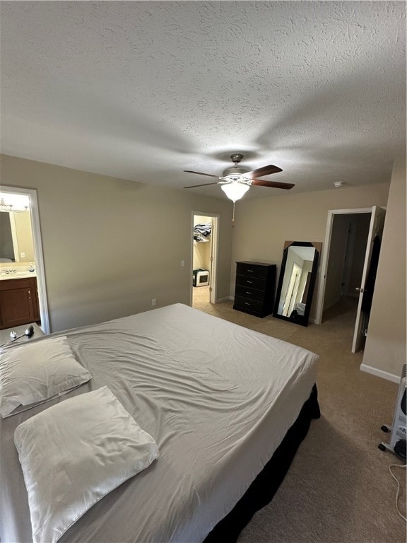 carpeted bedroom with a textured ceiling, connected bathroom, a walk in closet, and ceiling fan