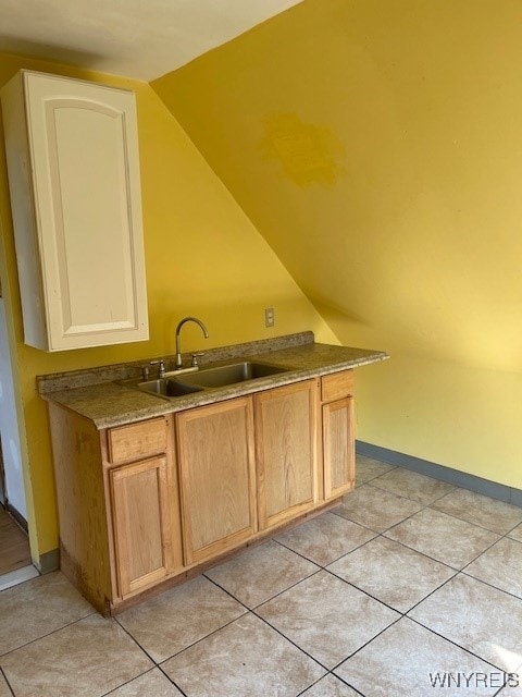 kitchen with light tile patterned flooring, lofted ceiling, and sink