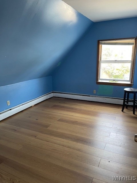 additional living space with lofted ceiling, baseboard heating, and light hardwood / wood-style floors