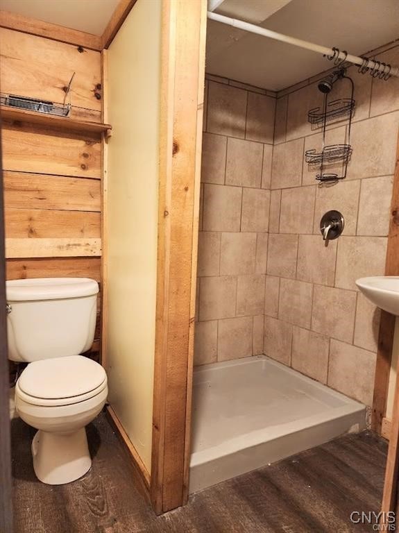 bathroom with toilet, hardwood / wood-style flooring, and a tile shower