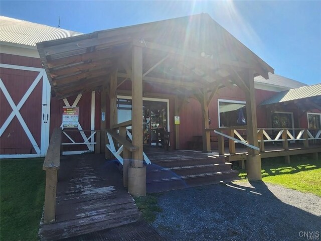 view of exterior entry with a lawn and a deck