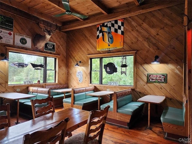 dining space with plenty of natural light, wood-type flooring, and wood walls