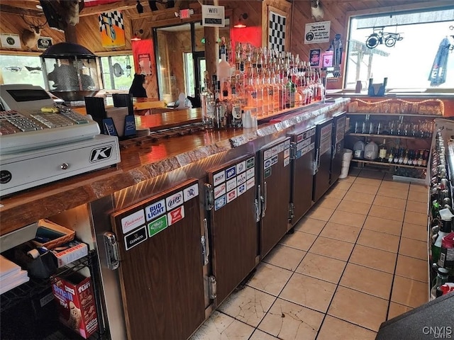 interior space with wood walls, light tile patterned floors, and dark brown cabinets