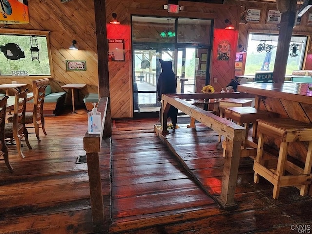 dining area with wood-type flooring, plenty of natural light, and wooden walls