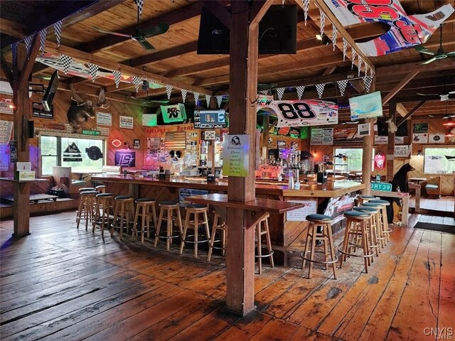 bar featuring wood ceiling, wood-type flooring, ceiling fan, and wooden walls