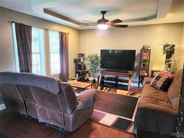 living room featuring a raised ceiling, wood-type flooring, and ceiling fan