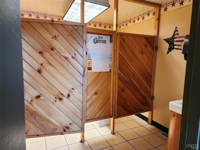 interior space with light tile patterned floors and wooden walls