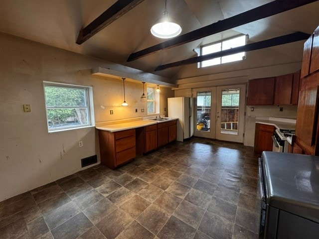 kitchen featuring lofted ceiling with beams, stainless steel stove, white fridge, and decorative light fixtures