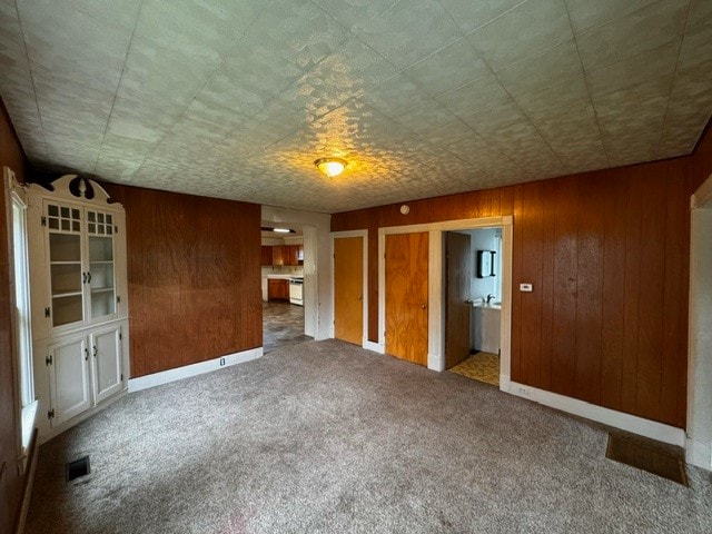 unfurnished room with carpet and wood walls