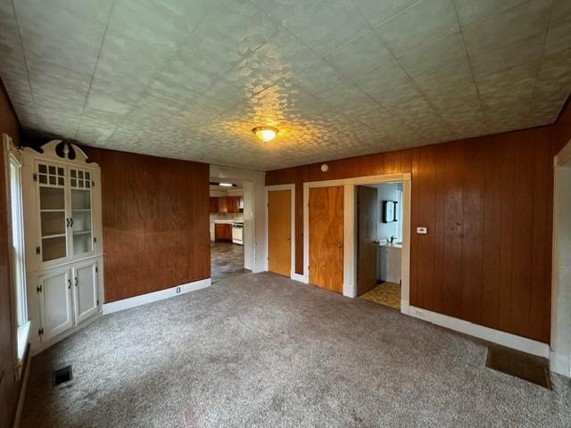 87 Canasawacta St, Norwich-City, NY 13815 - interior space with visible vents, wood walls, and carpet
