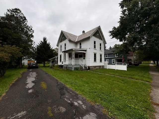 view of side of property with a porch and a lawn