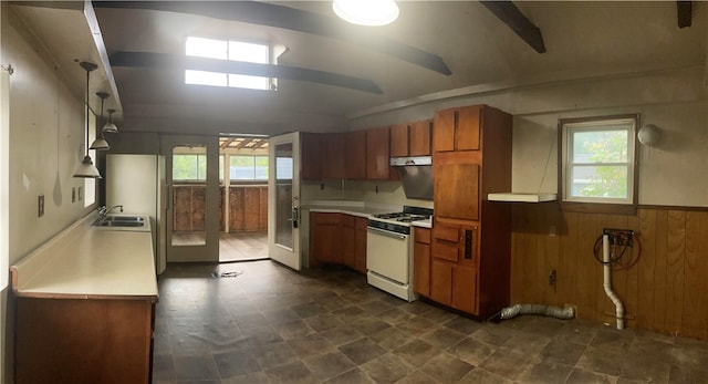 kitchen with ceiling fan, sink, wood walls, and gas range gas stove