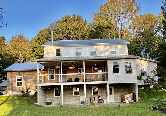 rear view of house with a lawn and a balcony