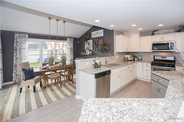 kitchen with stainless steel appliances, white cabinetry, sink, and kitchen peninsula