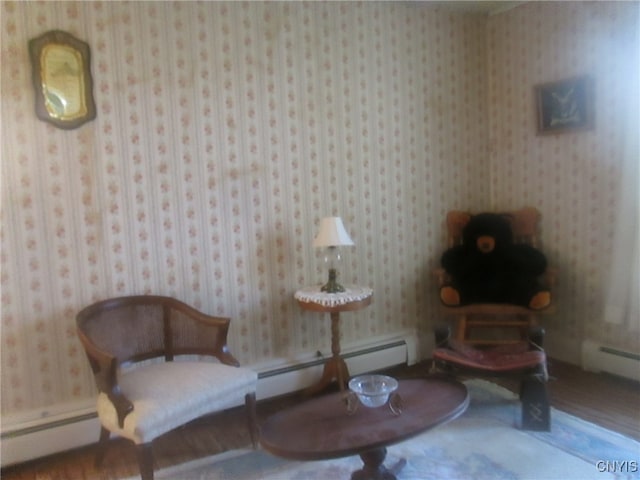 sitting room with a baseboard heating unit and wood-type flooring