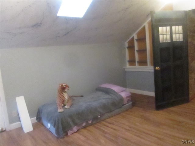 bedroom with vaulted ceiling and hardwood / wood-style flooring