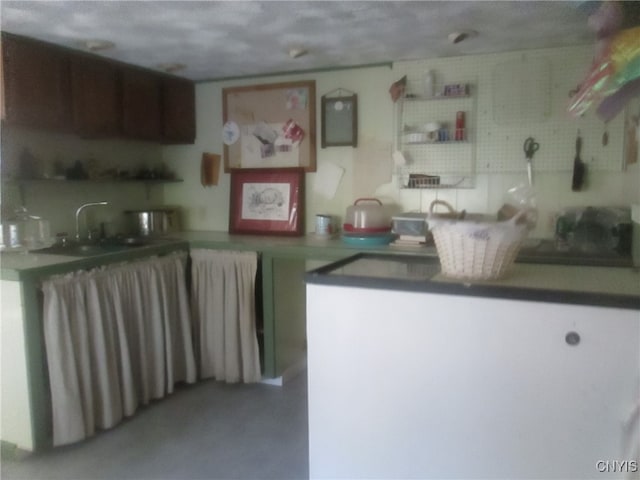 kitchen with concrete flooring, a textured ceiling, and kitchen peninsula