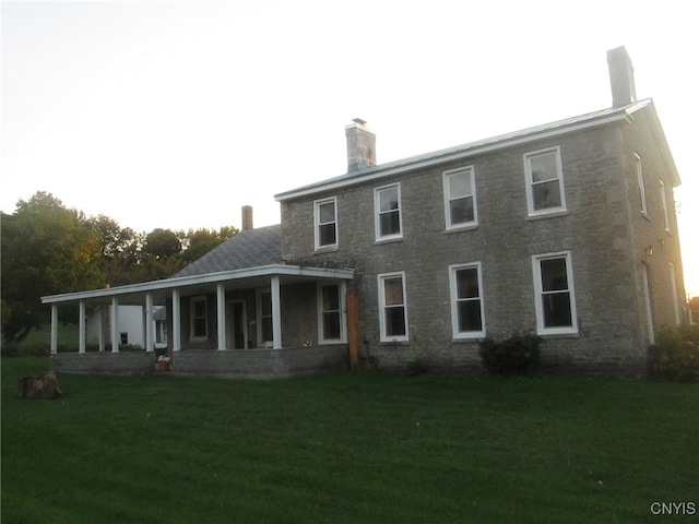 rear view of property featuring a lawn