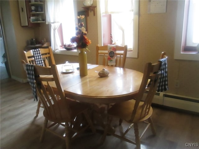 dining space with hardwood / wood-style floors, a baseboard heating unit, and plenty of natural light