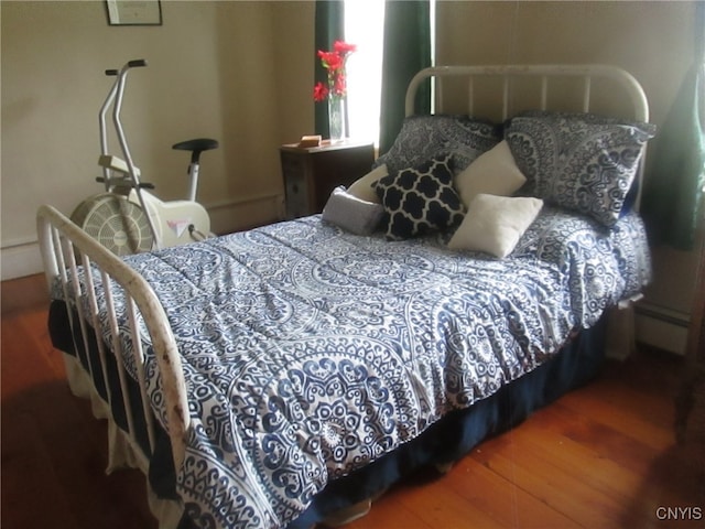 bedroom with a baseboard heating unit and hardwood / wood-style floors