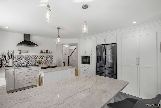 kitchen with wall chimney exhaust hood, black appliances, a center island, and white cabinets