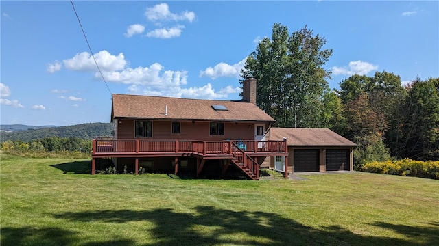 back of property featuring a yard, a garage, a deck, and an outbuilding