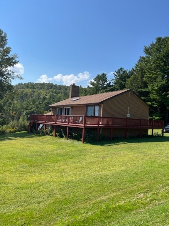 rear view of house featuring a yard and a wooden deck