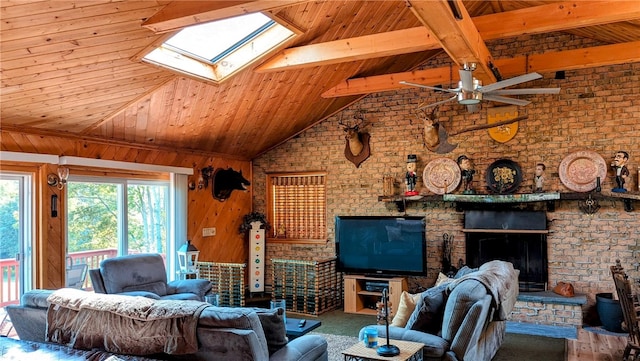 living room featuring a skylight, wooden ceiling, a large fireplace, brick wall, and ceiling fan