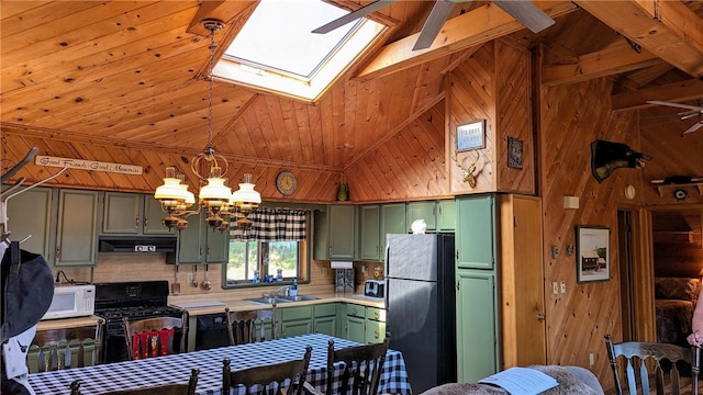 kitchen with ceiling fan with notable chandelier, lofted ceiling with skylight, green cabinets, black range oven, and stainless steel refrigerator