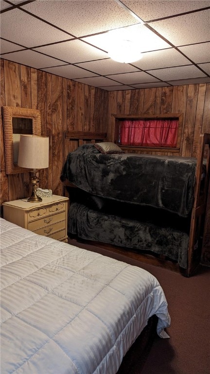 bedroom featuring a paneled ceiling and wood walls