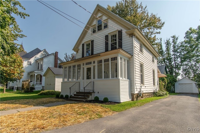 view of front facade with a front lawn, an outbuilding, and a garage