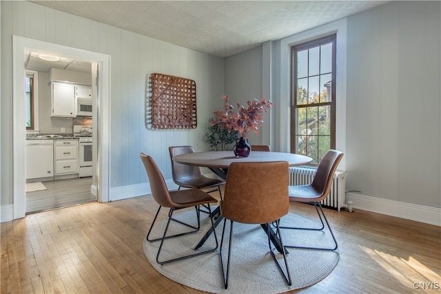 dining area with radiator heating unit and light wood-type flooring