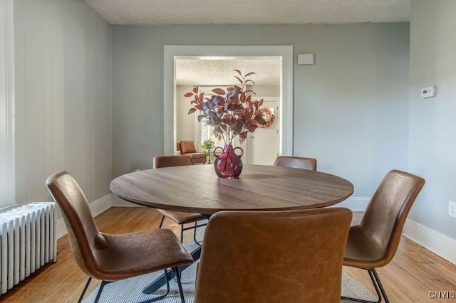 dining space with light hardwood / wood-style flooring and radiator heating unit