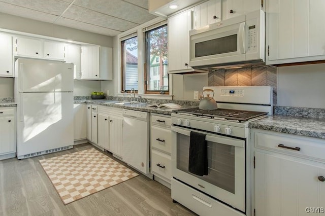 kitchen featuring white appliances, sink, a paneled ceiling, white cabinets, and light hardwood / wood-style flooring