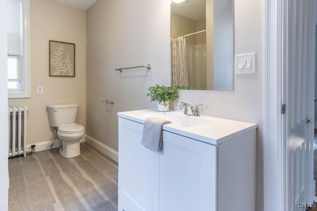 bathroom featuring toilet, radiator heating unit, vanity, and hardwood / wood-style floors