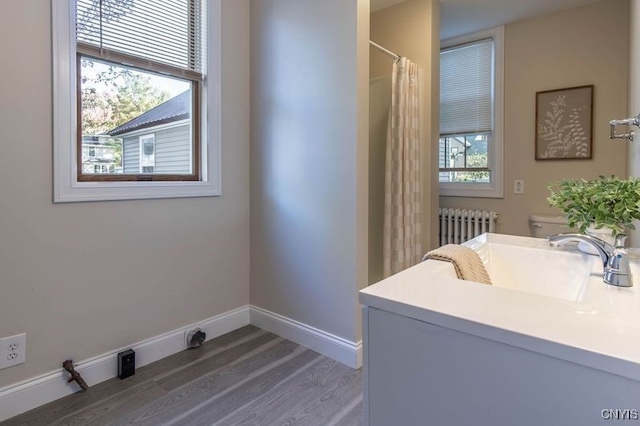 bathroom featuring toilet, radiator heating unit, a wealth of natural light, and hardwood / wood-style floors