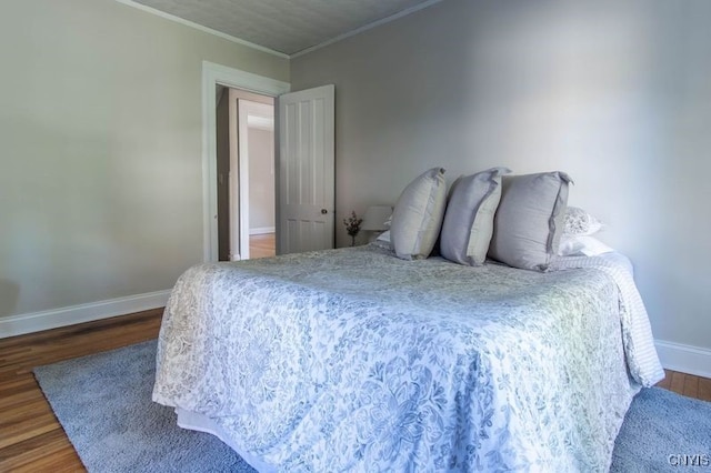 bedroom with ornamental molding and dark wood-type flooring