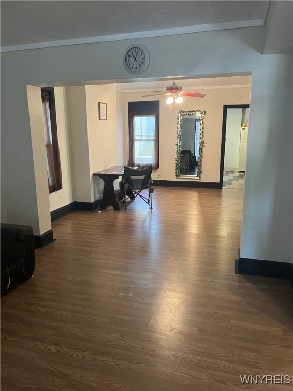 interior space featuring ornamental molding, ceiling fan, and dark wood-type flooring